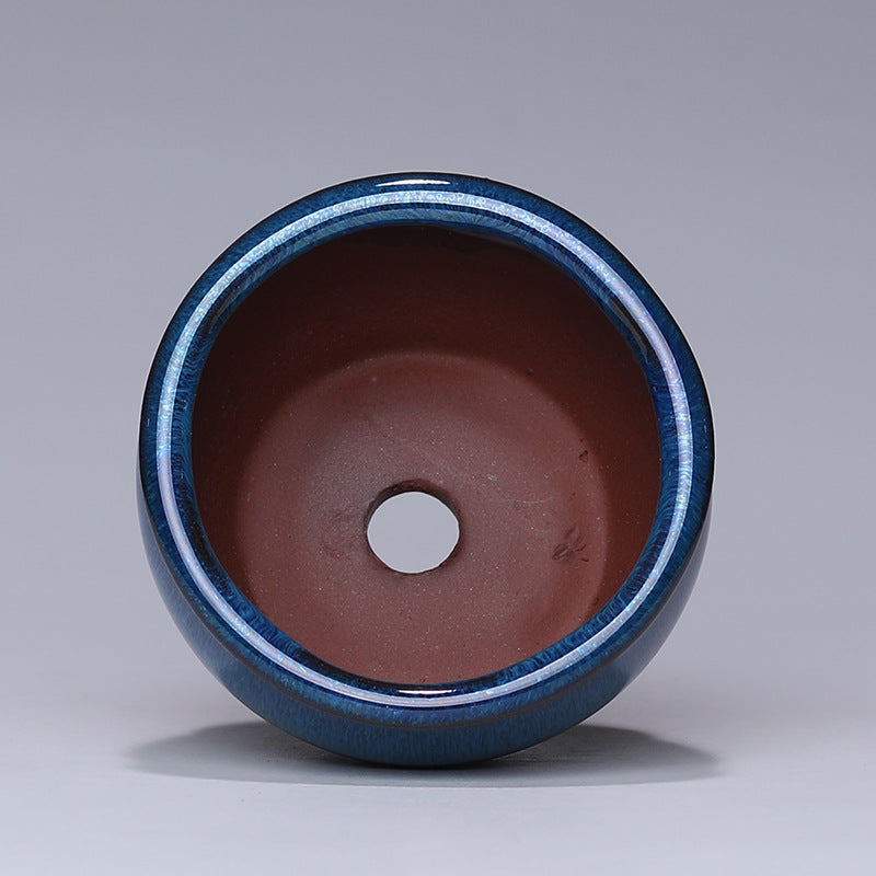 Ceramic pot with blue exterior and brown interior on a gray background
