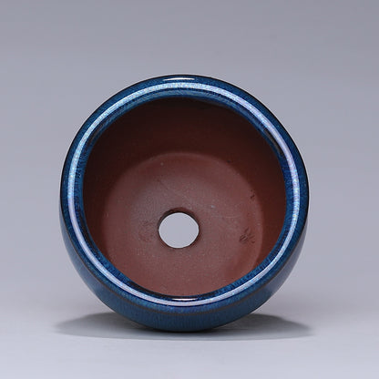 Ceramic pot with blue exterior and brown interior on a gray background