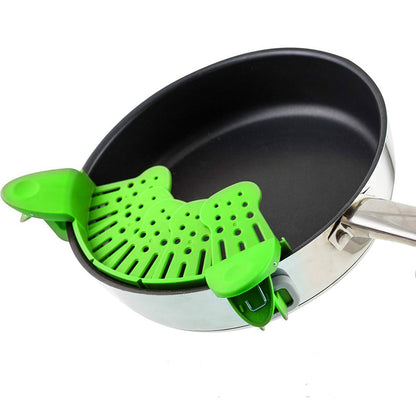 Green silicone strainer over a black frying pan on a white background