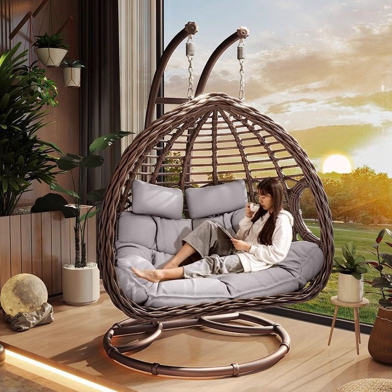 Person relaxing in a hanging egg chair with a scenic view outside