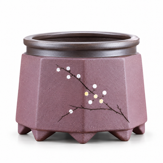 A hexagonal ceramic planter pot in a muted mauve-purple color, featuring a hand-painted branch design with white and yellow blossoms on the front, set against a plain white background.
